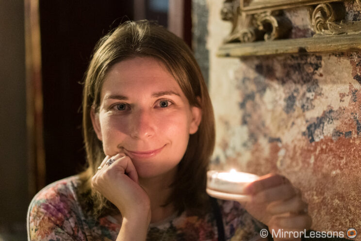 Headshot portrait of a young woman holding a candle in a low light location
